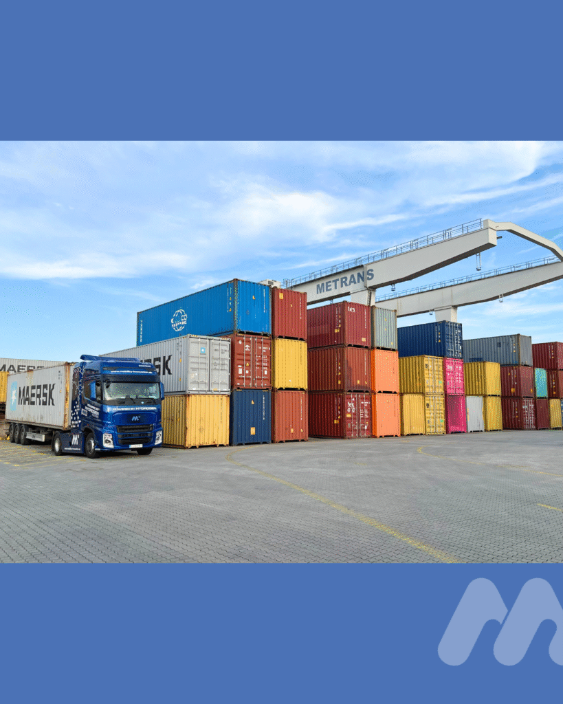 Vodíkový ťahač s kontajnerom Maersk v priestore prekládky medzi farebnými kontajnermi v logistickom areáli METRANS.